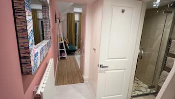 A hallway with a radiator, a white door, and a shower area.