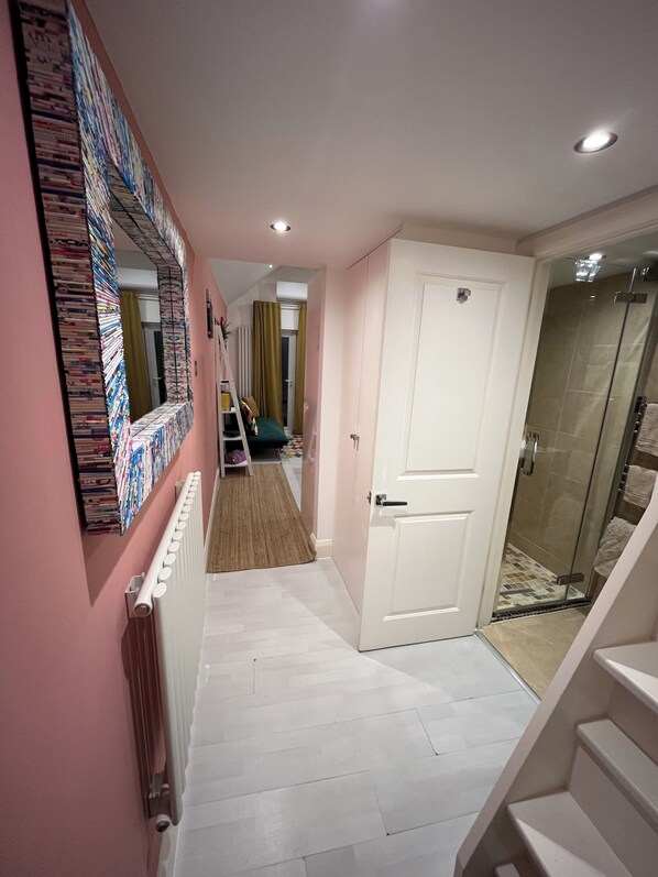 A hallway with a radiator, a white door, and a shower area.