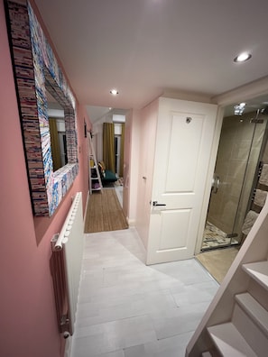 A hallway with a radiator, a white door, and a shower area.