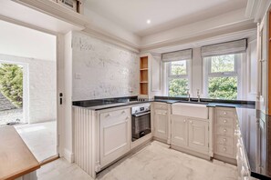 A modern kitchen with white cabinetry, a black countertop, and a built-in oven. - The Lodge (Leominster)