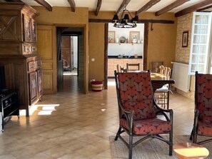 A spacious living room with a fireplace, a dining area with a table and chairs, and a kitchen in the background. - Country House with Pool in the Dordogne (Area: Cénac, Domme, La Roque-Gageac) (Cénac-et-Saint-Julien)