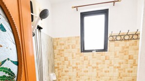 Un bagno con il water, una doccia con soffione a mano e una finestra.