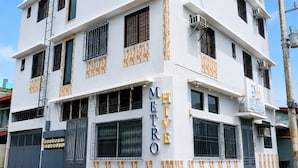 Un edificio a più piani con facciata bianca, diversi balconi e una segnaletica che indica che si tratta di un albergo.