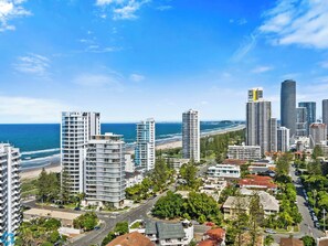 Eine Küstenstadtlandschaft mit Wolkenkratzern, einem Strand und blauem Himmel.