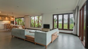 A modern living room with a sofa, TV, and dining area with chairs and a table. - Ombak D3 Villa by Betterplace (Cemagi)