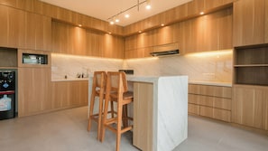 Eine moderne Küche mit Holzschränken, einer Marmorarbeitsplatte und einer eingebauten Mikrowelle.