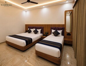 A hotel room with two beds, a ceiling fan, a nightstand, a mirror, and a curtain.