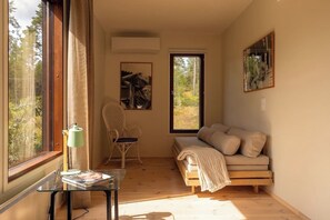 A cozy room with a sofa, a chair, a table with a lamp, and a large window offering a view of trees. - Stay North - Viitala (Salo)