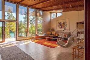 A spacious living room with large windows, a hanging chair, and a cozy seating area. - Stay North - Viitala (Salo)