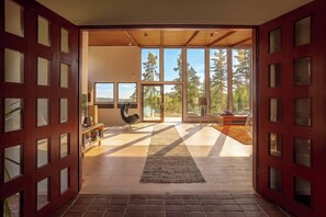An interior space with a large window, a wooden floor, and a rug leading to an outdoor area.