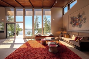 A spacious living room with large windows, a red rug, a sofa, and a coffee table. - Stay North - Viitala (Salo)