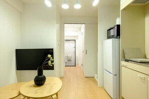A compact kitchen with a microwave, refrigerator, and a small dining table with a vase.