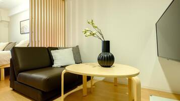 A modern living room with a sofa, a round wooden table, and a vase with flowers.