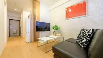 Uma sala de estar moderna com televisão de tela plana, um sofá, uma mesa de centro e um quadro na parede.