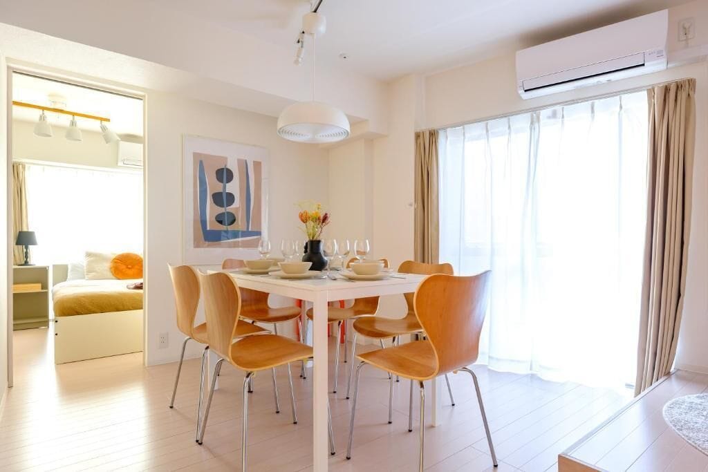 A modern dining room with a round table, multiple chairs, and a vase of flowers.