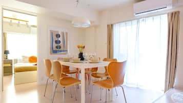 A modern dining room with a round table, multiple chairs, and a vase of flowers.