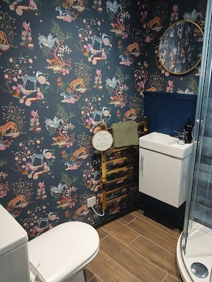 Ein Badezimmer mit dunkel gemusterten Wänden, einer weißen Toilette, einem Waschbecken mit Spiegel und einem Handtuchhalter.