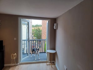 A room with a sliding glass door leading to a balcony, a small round table, and a standing lamp.