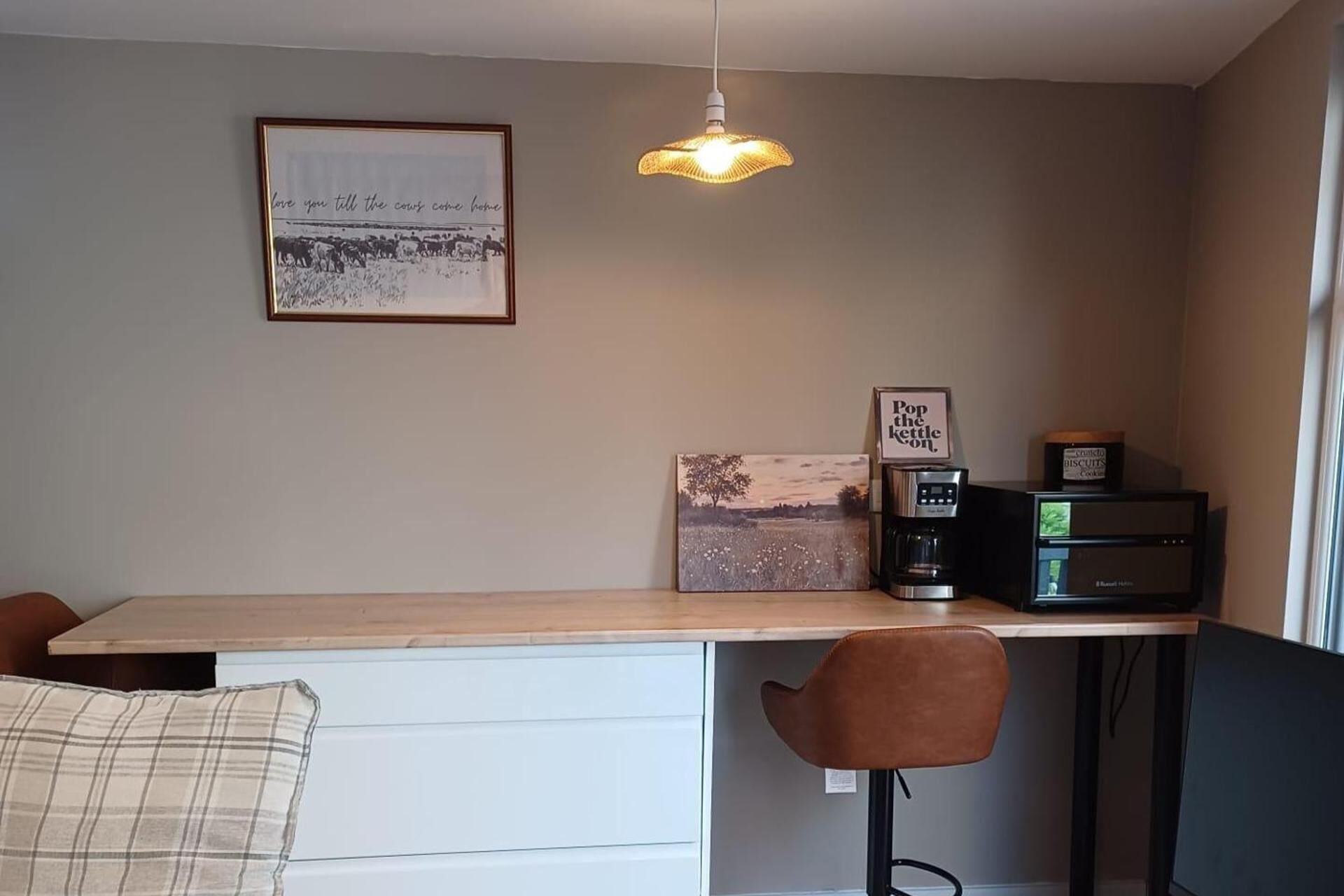 Una cocina moderna con encimera de madera, una cafetera y un cuadro en la pared.