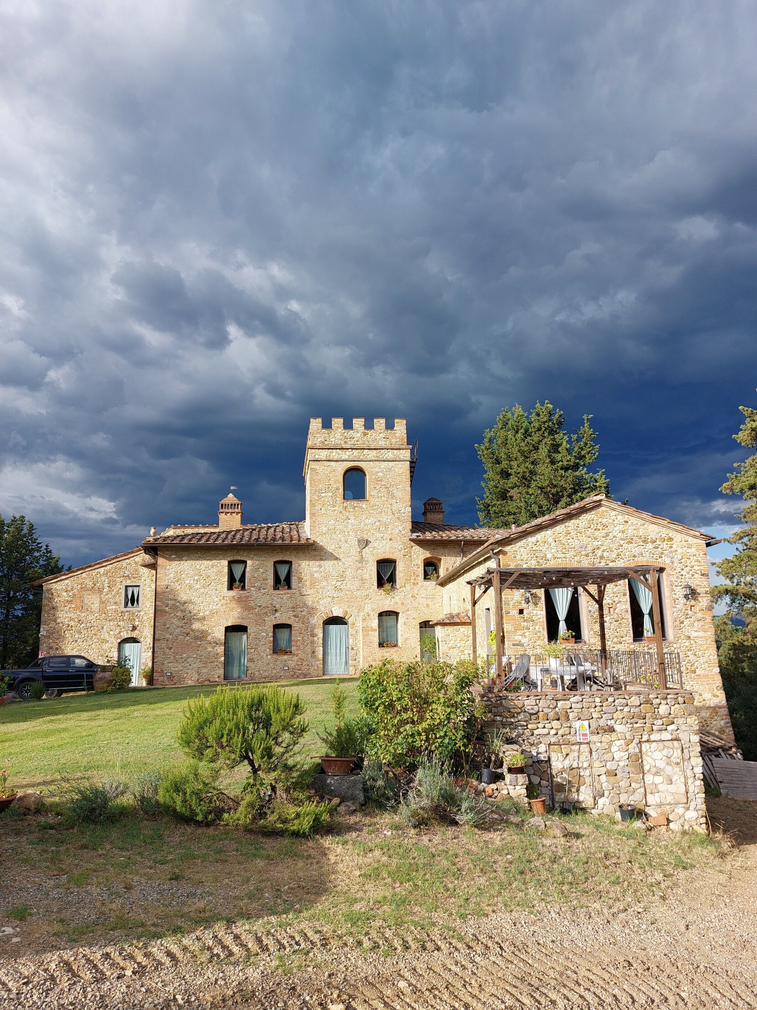 Un edificio de piedra con una torre central, varias ventanas y un porche cubierto.