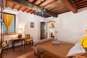 A bedroom with a bed, a chair, a desk, a lamp, and a chandelier. - Rosmarinus Apartment – Two-Room Flat with Views of Tuscan Vineyards (San Casciano In Val di Pesa)