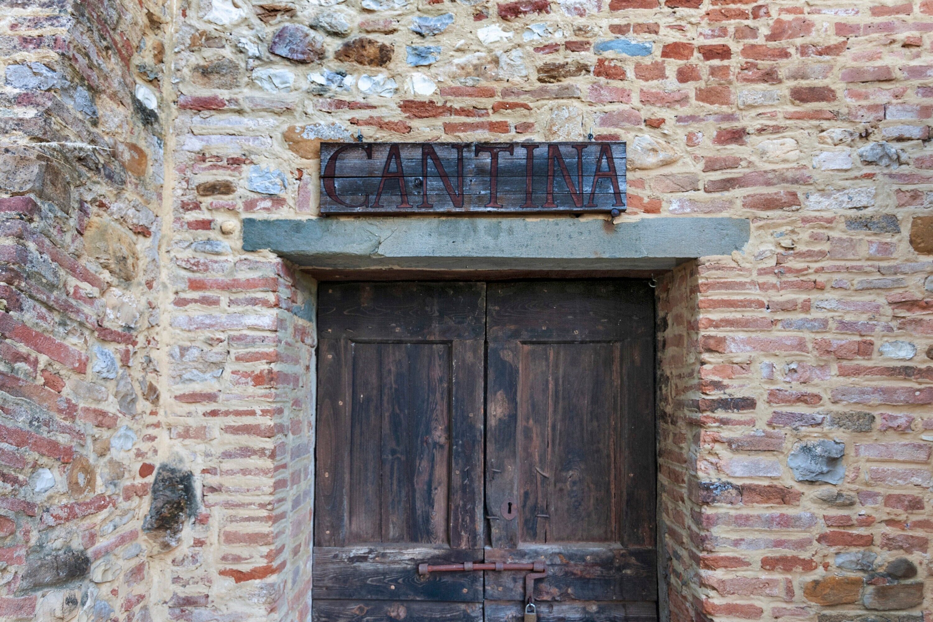 A rustic wooden door with a metal sign above it.
