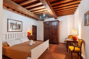 Une chambre à coucher avec un lit, une armoire en bois, un bureau avec une chaise et un lustre.