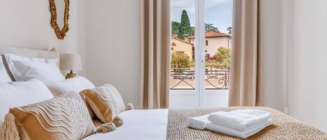 Een hotelkamer met een bed, uitzicht en een balkon.
