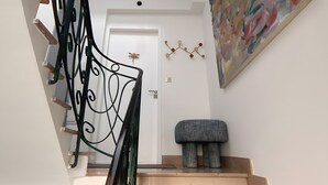 A staircase with a black metal railing, a light fixture above, a door at the top, and a painting on the wall. - "La Grande Terrasse" Apartment with 40m2 Private Terrace, Wi-Fi, and Air Conditioning (Cannes)