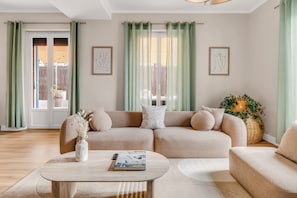 Ein Wohnzimmer mit einem beigefarbenen Ecksofa, einem Couchtisch und einer Topfpflanze.