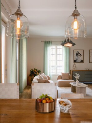 A living room with a sofa, a coffee table, and a dining table with fruit and bread. - "La Grande Terrasse" Apartment with 40m2 Private Terrace, Wi-Fi, and Air Conditioning (Cannes)