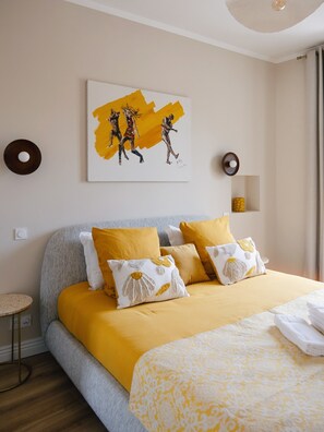Ein Hotelzimmer mit einem Bett, Kissen, einem kleinen runden Tisch und einem Bild an der Wand.