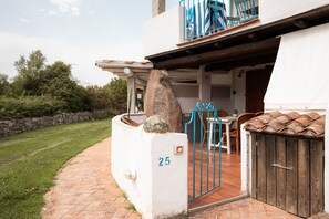 Una casa con un pilar de piedra, un cartel con el número 25, un portón azul y una puerta de madera.