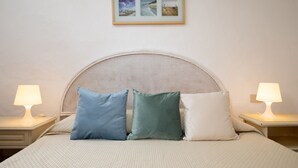Una cama con cabecera de mimbre, dos lámparas de noche y tres almohadas.