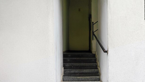 A narrow stairway leading to a door with a metal handrail. - Collection O Jupiter Hospital Thane West (Mumbai)
