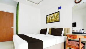 A hotel room with a bed, a desk with a chair, a mirror, a clock, and a Buddha painting. - Collection O Jupiter Hospital Thane West (Mumbai)