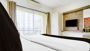 A hotel room with a large bed, a flat-screen TV mounted on the wall, and a window with curtains. - Collection O Jupiter Hospital Thane West (Mumbai)