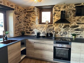 A kitchen with stone walls, a built-in oven, and a window with a picture frame.