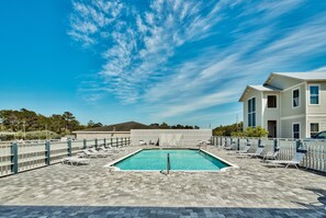 A rectangular swimming pool with a tiled deck, surrounded by lounge chairs and a white fence. - Welcome Home to 30A – FREE Golf Cart (Santa Rosa Beach)