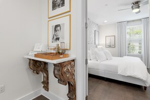 A bedroom with a bed, white bedding, a bedside table with a lamp, and a wall-mounted mirror. - Welcome Home to 30A – FREE Golf Cart (Santa Rosa Beach)