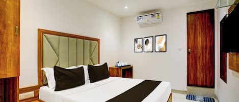 Una habitación de hotel con cama, mesitas de noche, teléfono, aire acondicionado instalado en la pared y cuadros enmarcados.