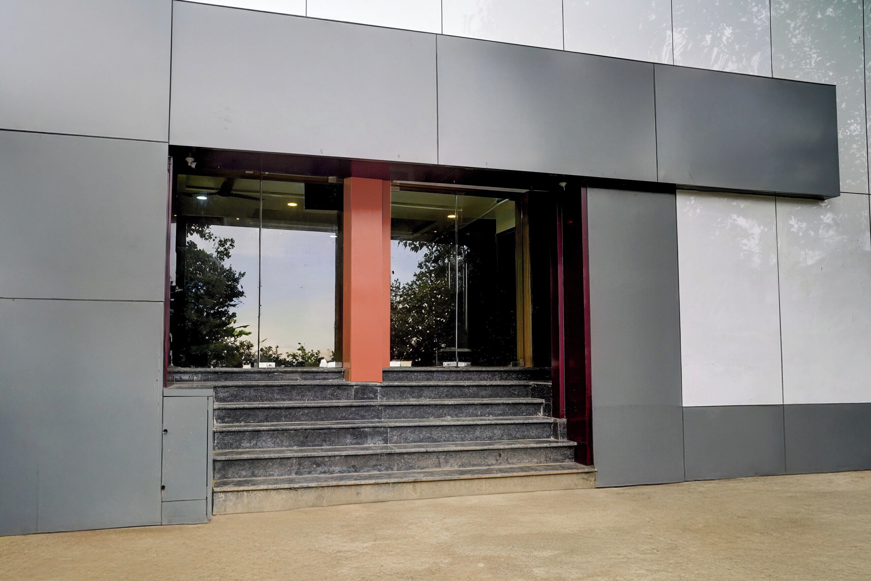 Une entrée moderne, avec un escalier menant à une porte en verre.