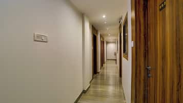 A hotel hallway with wooden doors, a marble floor, and a light switch on the wall.