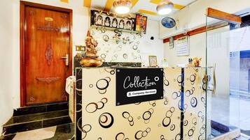 Un área de recepción con una puerta de madera, un mostrador de recepción con un letrero que dice 'Collection' y un calendario en la pared.