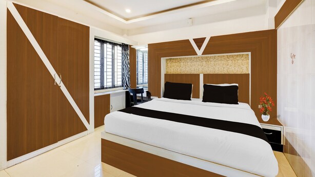 Une chambre moderne avec un grand lit, un bureau et une fenêtre équipée de stores.