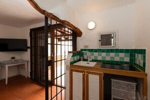 Eine Küche mit Spüle, einem Fenster und einem an der Wand befestigten Fernseher.
