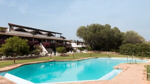 Une piscine dotée d’une terrasse carrelée, entourée d’une pelouse et d’arbres.