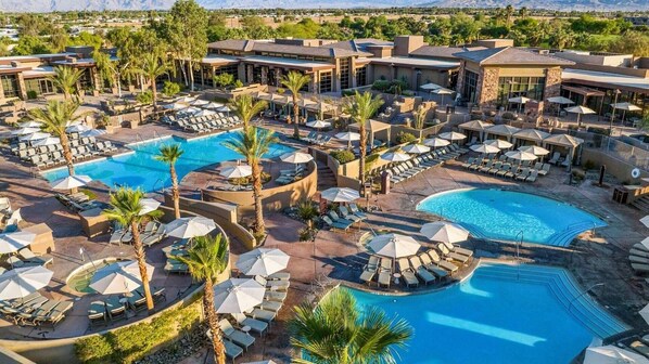Un resort con varias piscinas, tumbonas y sombrillas.