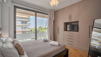 A bedroom with a bed, a TV, and a sliding glass door to a balcony.