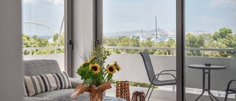 A modern living room with a sofa, a coffee table, and a view of a marina through large windows.